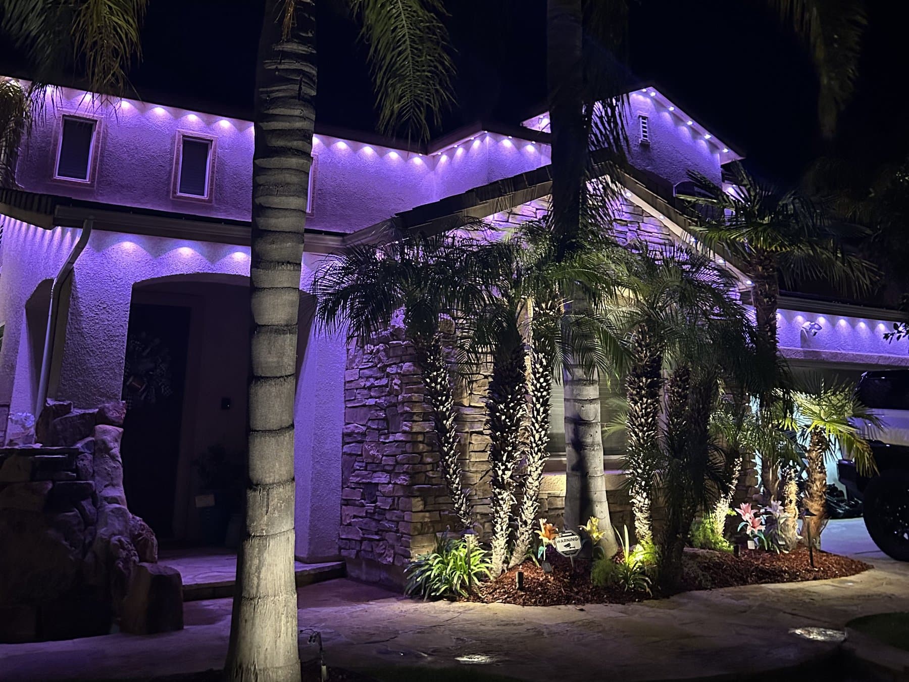 Permanent roofline lighting running purple across the eaves at night